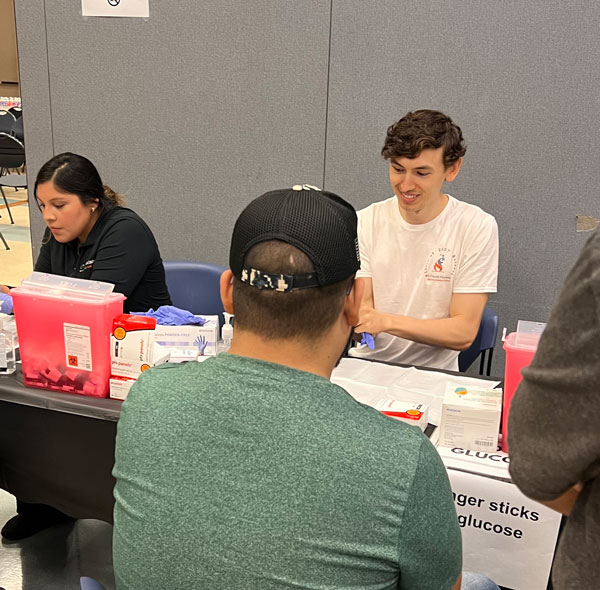student volunteers screening patients blood pressure