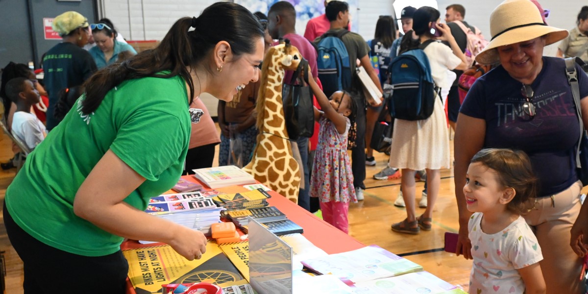 UTH team member interacts with little girl at community event.